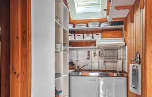 A compact kitchen with wooden cabinets, a built-in oven, and a window above the sink.