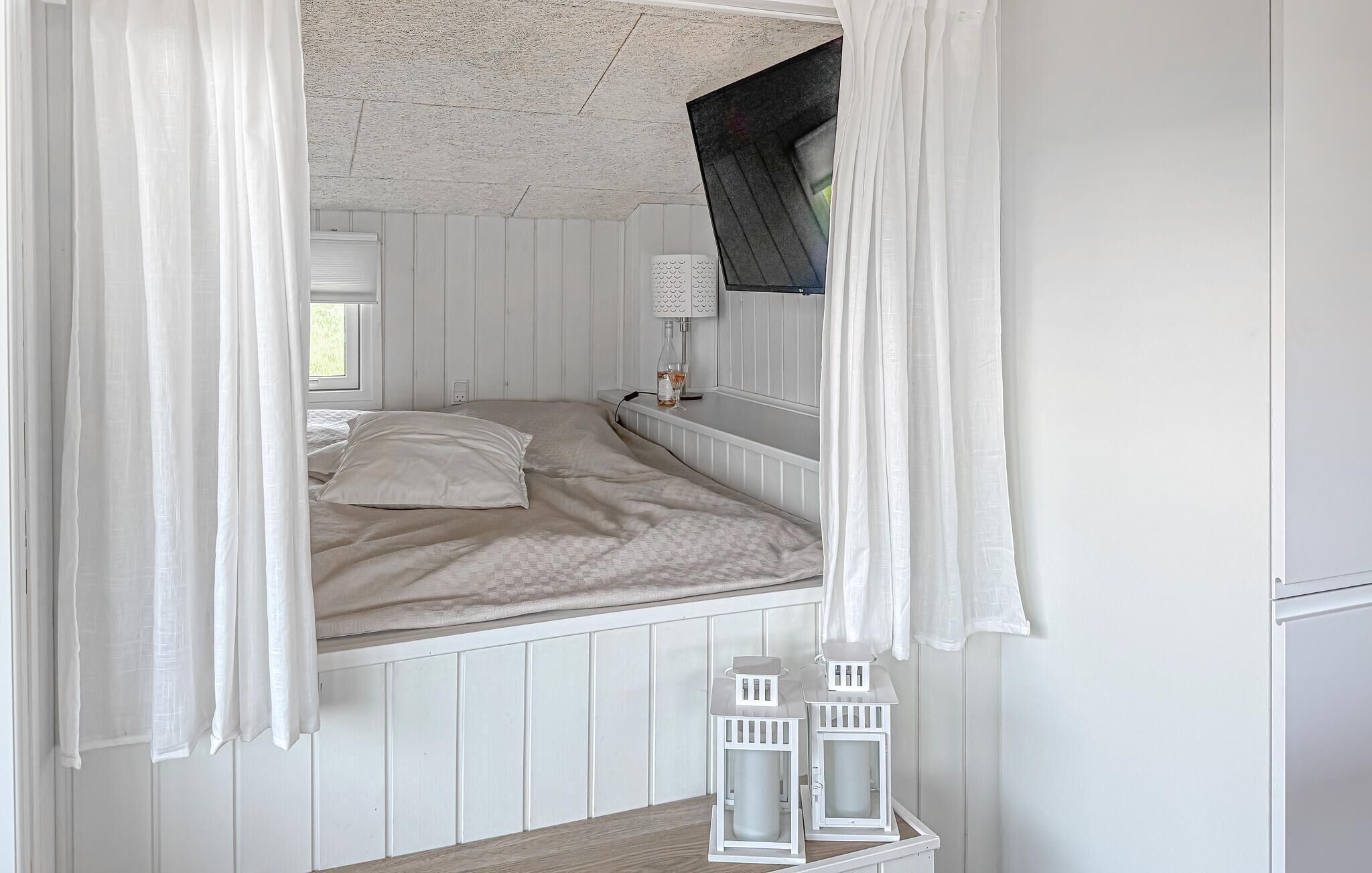 A bedroom with a bed, a nightstand, a lamp, and a window with curtains.