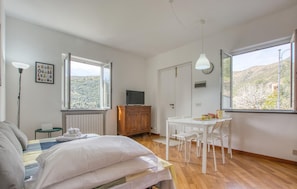 Un dormitorio con cama, mesita de noche, lámpara y vistas a un paisaje montañoso por la ventana.