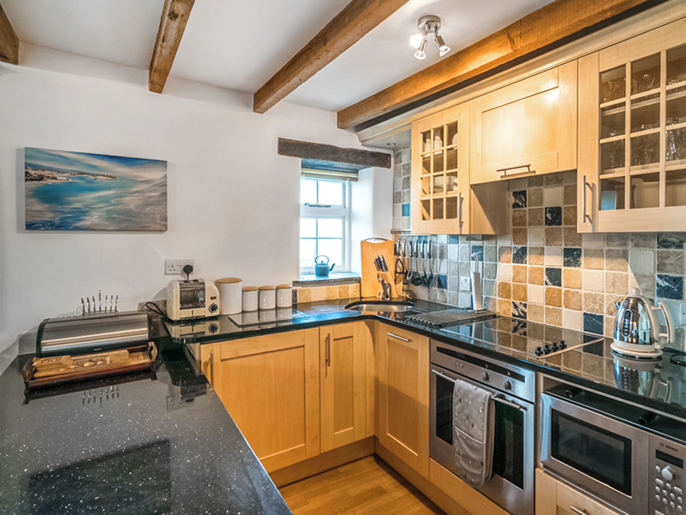 A modern kitchen with wooden cabinets, a black countertop, and stainless steel appliances.
