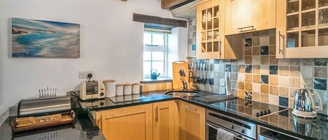 A modern kitchen with wooden cabinets, a black countertop, and stainless steel appliances.