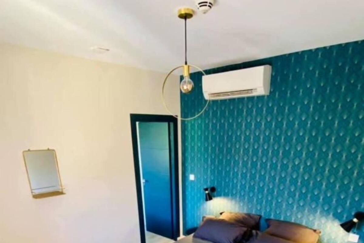 Une chambre à coucher comprenant un lit, une porte, un appareil de climatisation et un luminaire fixé au mur.