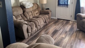 A living room with a beige sofa, a lamp, and a door with a blue curtain. - Cozy cottage near the falls (Idaho Falls)