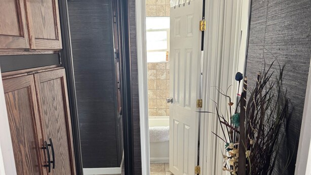 A hallway with dark wood flooring, white doors, and a vase with dried plants. - Cozy cottage near the falls (Idaho Falls)