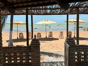 Een uitzicht op het strand met parasols, ligstoelen en helder zicht op de zee.