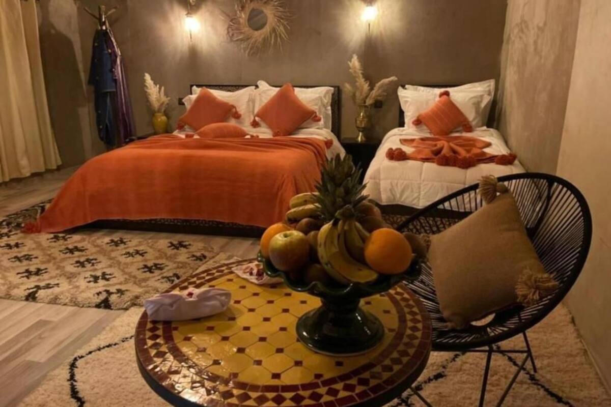Una camera d'albergo con due letti, un tavolino con della frutta e una sedia.