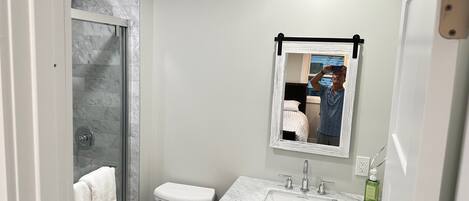 Une salle de bain équipée d’une douche, de toilettes, d’un lavabo et d’un miroir.