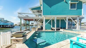 En ejendom ved vandet med swimmingpool, udendørs siddeplads og en overdækket terrasse.
