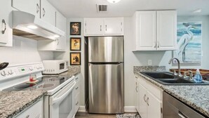 Una cocina moderna con armarios blancos, electrodomésticos de acero inoxidable, encimeras de granito y horno empotrado.