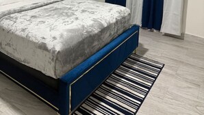 Une chambre à coucher comprenant un lit, un ventilateur de plafond, une table de chevet et un téléviseur fixé au mur.