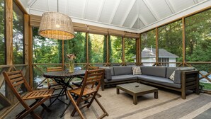 A covered patio with a table and chairs, a sofa, and a hanging light fixture. - 2027 OPEN! Gorgeous Lakeside Home With Pool, Hot Tub, And More! (Lakeside)