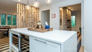 A modern kitchen with a large island, wooden wall decor, and pendant lighting. - 2027 OPEN! Gorgeous Lakeside Home With Pool, Hot Tub, And More! (Lakeside)