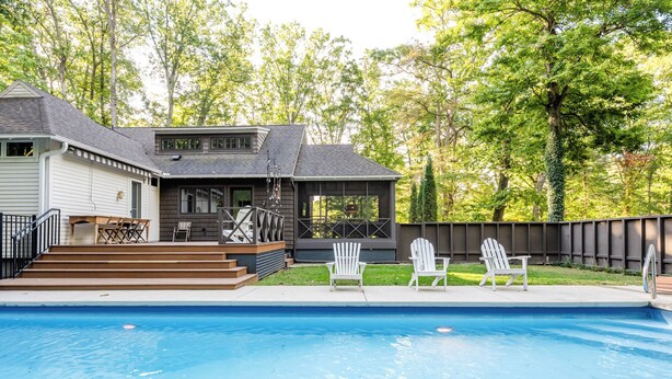 A backyard with a swimming pool, a covered patio area, and a wooden deck. - 2027 OPEN! Gorgeous Lakeside Home With Pool, Hot Tub, And More! (Lakeside)