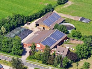 An industrial building with solar panels on the roof, surrounded by greenery and a road. - Holiday Home 'Seestern' with Private Terrace, Shared Garden and Wi-Fi (Wangerland)