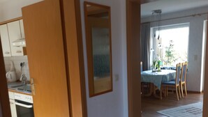 Avokeittiö, jossa on ruokailutila, puuovet ja laattalattia.