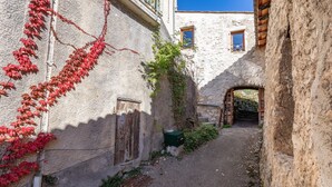 A narrow alley with a rustic stone building, a wooden door, and a small window. - Gîte 'Gite De Pascal Et Virginie' with Mountain View, Private Terrace and Balcony (Ponet-et-Saint-Auban)