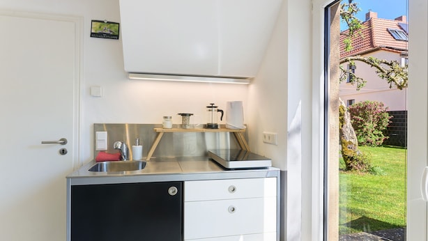 Una cucina compatta con lavello, macchina del caffè e un piccolo piano di lavoro.