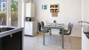 Una cucina moderna con lavastoviglie integrata, un tavolo da pranzo con sedie e un piccolo frigorifero.