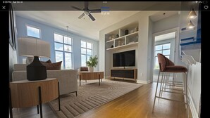 A modern living room with a sofa, coffee table, TV stand, and bar stools. - Long term stay Exquisite penthouse apartment in Raleigh. (Raleigh)
