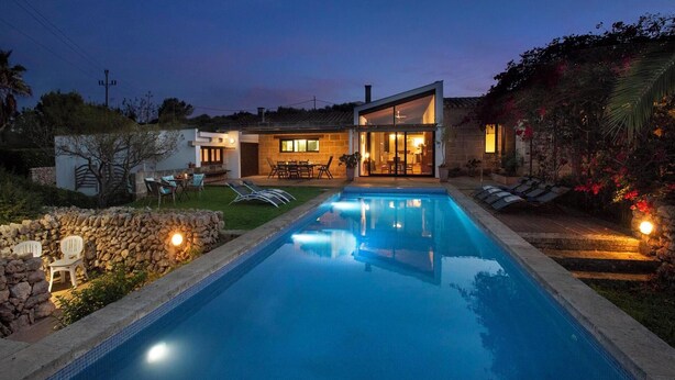 Ein modernes Haus mit Schwimmbad, Sitzgelegenheit im Freien und einer gut beleuchteten Terrasse.