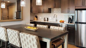 A modern kitchen with a large island, dark wood cabinets, stainless steel appliances, and a breakfast bar with cushioned chairs. - Charming 2-bedroom Ski-in, Ski-out resort in lovely Steamboat Springs (Steamboat Springs)