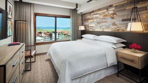 A modern hotel room with a large bed, a wooden accent wall, a view of the countryside, and a desk with drawers. - Charming 2-bedroom Ski-in, Ski-out resort in lovely Steamboat Springs (Steamboat Springs)