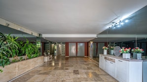 A spacious lobby with a marble floor, a reception desk, and a large mirror reflecting the interior. - Apartment 'Ocean View Dunas De Artola' with Sea View, Wi-Fi and Air Conditioning (Marbella)