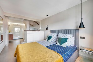 A modern bedroom with a bed, bedside tables, and a staircase leading to an upper level.