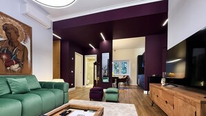 A modern living room with a green sofa, wooden coffee table, and a flat-screen TV. - THE HOUSE OF JANUS (Ciampino)