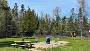 Zona de picnic con una mesa y sillas de madera, rodeada de un bosque.