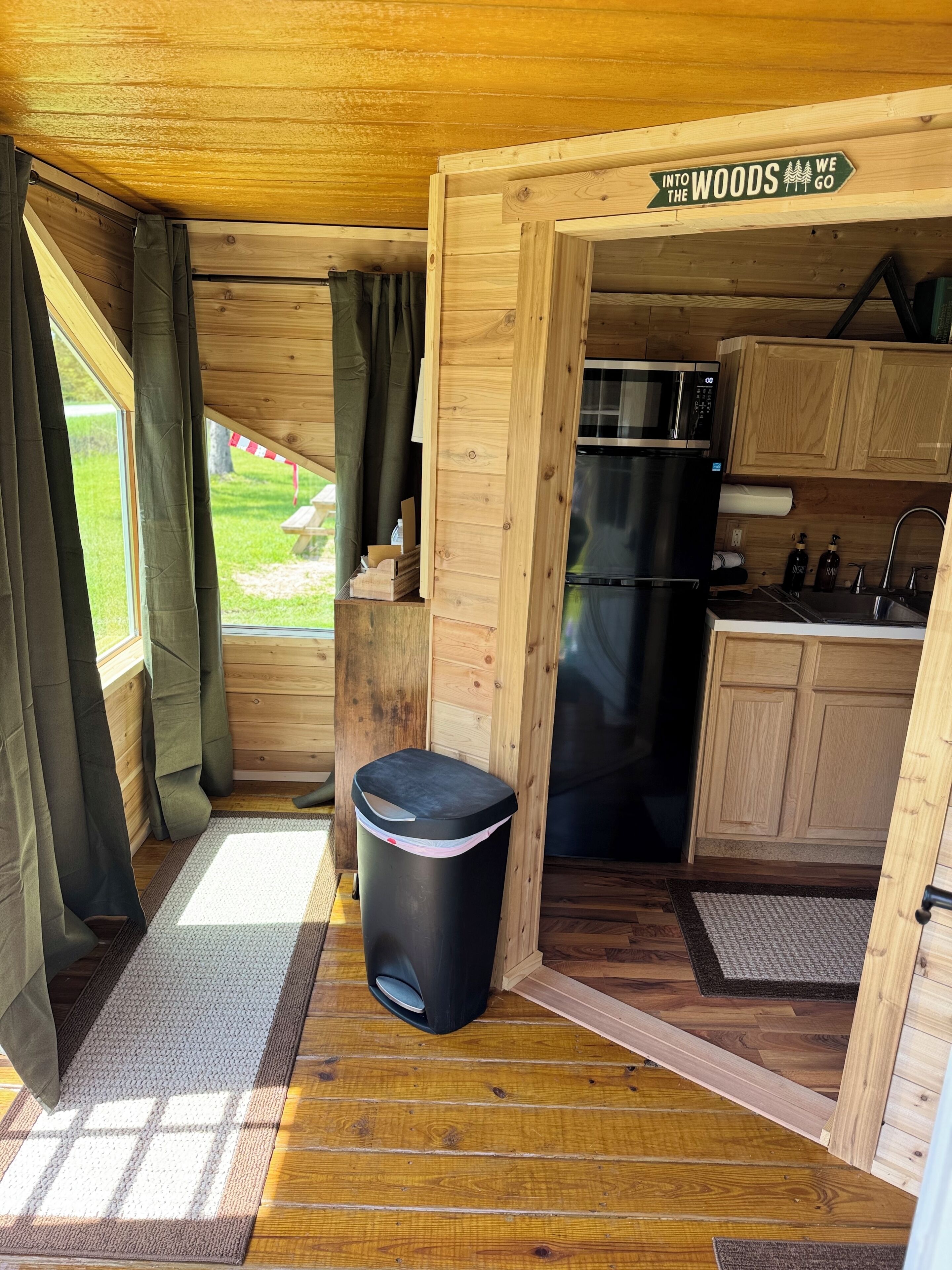 A compact kitchen with wooden cabinets, a microwave, and a refrigerator.