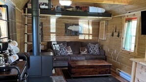 A cozy cabin interior with a fireplace, wooden furniture, and a tiled floor. - Rustic tiny cabin-WiFi & power, close to beach, boat launch, lighthouse, trails (Rapid River)