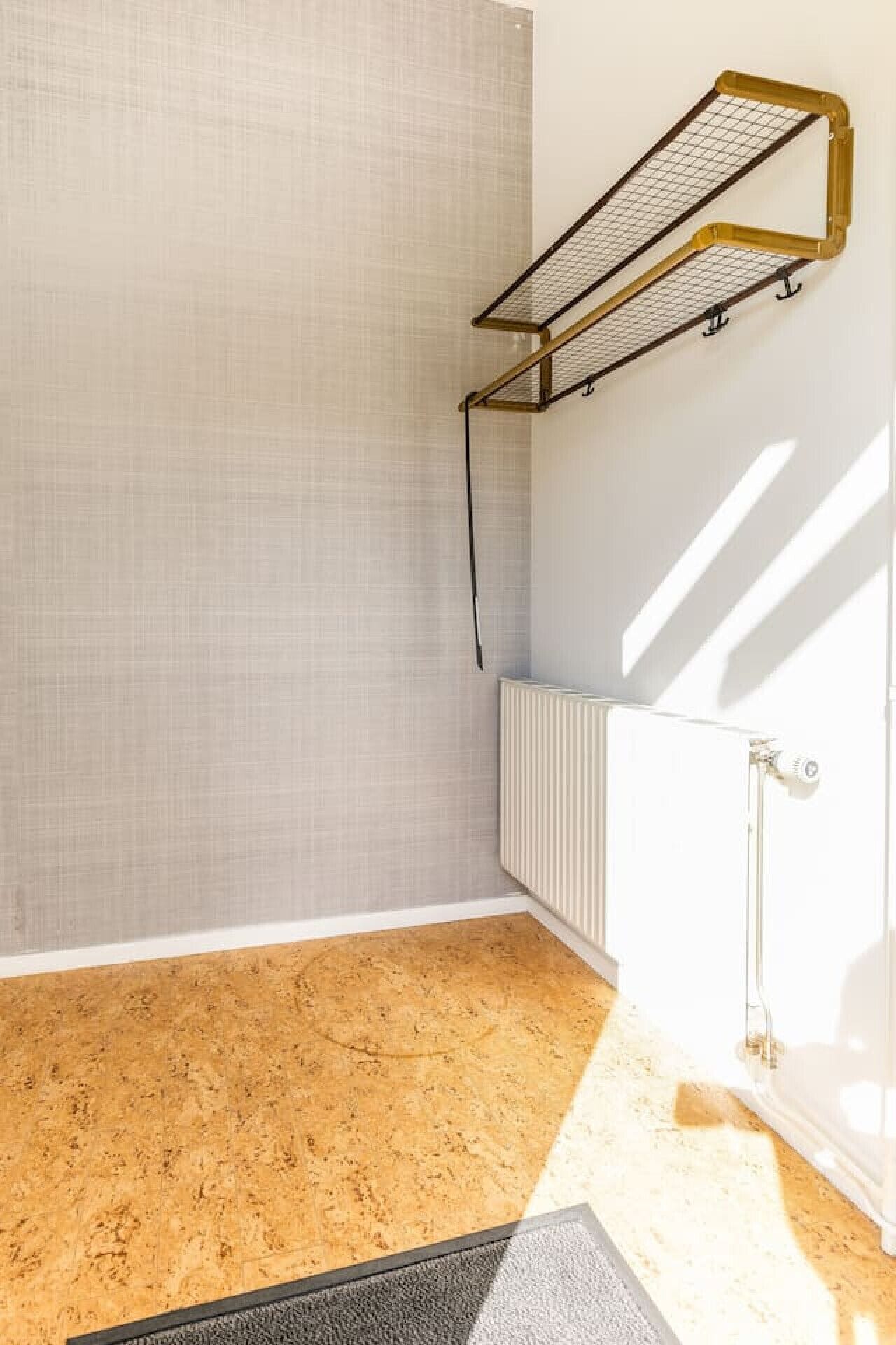 A room with a radiator, a window with blinds, and a wooden floor.