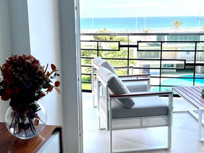 Una habitación moderna con vistas al océano, una piscina y un balcón con mobiliario exterior.