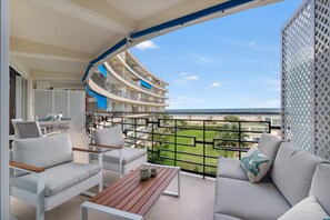 Un balcón con vista al mar, un sofá, una mesa y una silla.