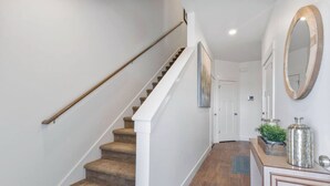 A staircase with wooden handrails and carpeted steps leading to a door. - 3BR, 2.5BA Townhome - Great Location + Open-Layout + Modern (Rexburg)