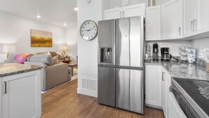 A modern kitchen with white cabinets, stainless steel appliances, and a granite countertop. - 3BR, 2.5BA Townhome - Great Location + Open-Layout + Modern (Rexburg)