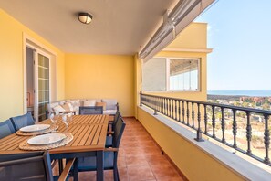 A balcony with a dining table set for two, a sofa, and a view of the sea. - Laderas - FRONT SEA VIEW (Arona)