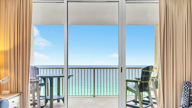Una habitación con puerta corrediza de vidrio que da a un balcón con vistas al océano.