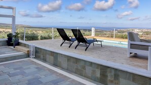 An outdoor patio with a pool, two lounge chairs, and a view of the landscape. - Theasis Serenity Residence, Secluded Private Pool Retreat with Sea View (Sitia)