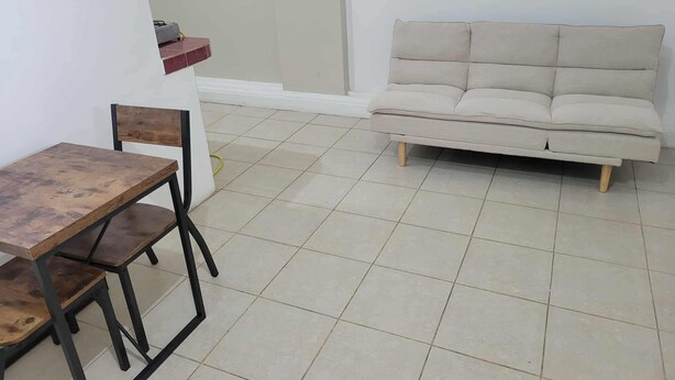 A small, clean room with a wooden dining table and chairs, a beige sofa, and a tiled floor. - Pacific Paradise in Ecuador (Manta)