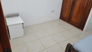 A small room with a bed, a white bedside table, and a wooden wardrobe. - Pacific Paradise in Ecuador (Manta)