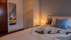 A hotel room with a bed, a nightstand, a lamp, a wardrobe, and a mirror. - Casa di Leonardo by Wonderful Italy (Turin)