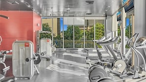 Ein Fitnessstudio mit Laufbändern, Kraftgeräten und einer roten Wand.