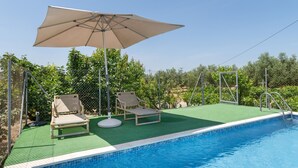 Een zwembad met twee ligbedden en een parasol.