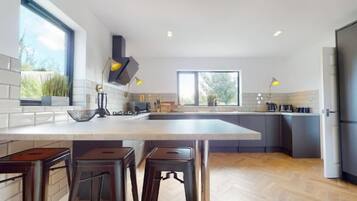 A modern kitchen with a large island, bar stools, and a view of the outdoors.