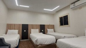A hotel room with three single beds, a desk, and a chair. - City Luxury Serviced Apartments (Madinah)