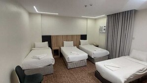 A hotel room with three single beds, a desk, and a chair. - City Luxury Serviced Apartments (Madinah)