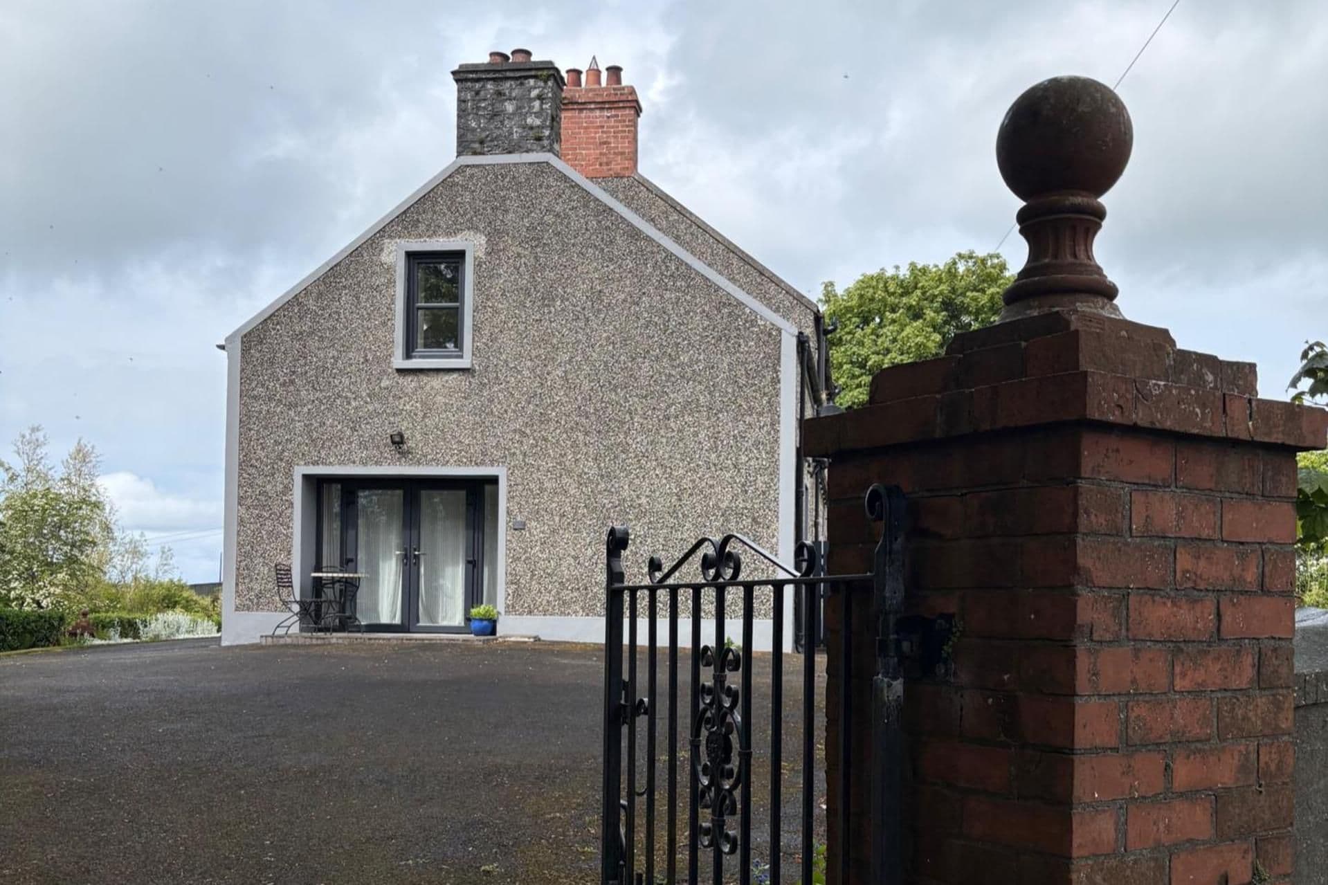 A stone building with a large garage door, a small window, and a brick entrance gate.