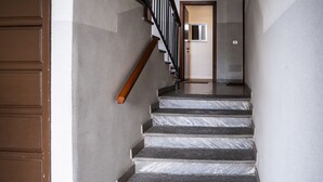 Un escalier avec une rampe en bois, des marches en marbre et une porte en haut.